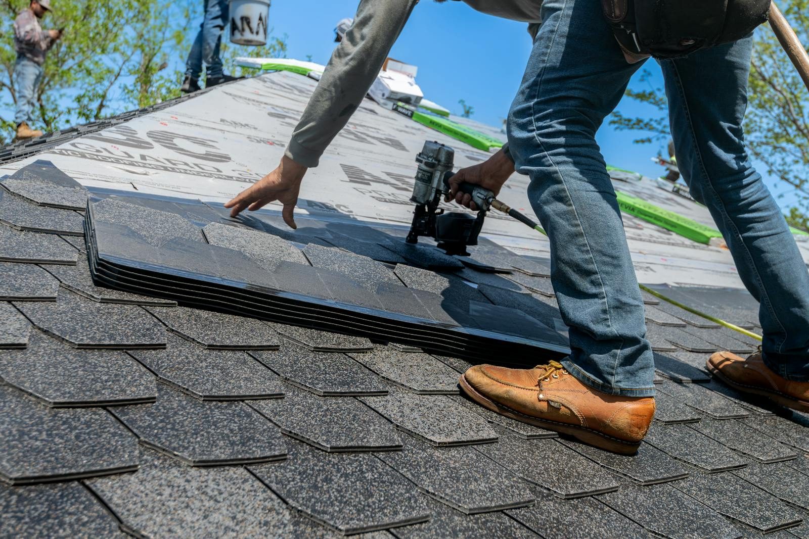 Roofer installing asphalt shingle with nail gun
