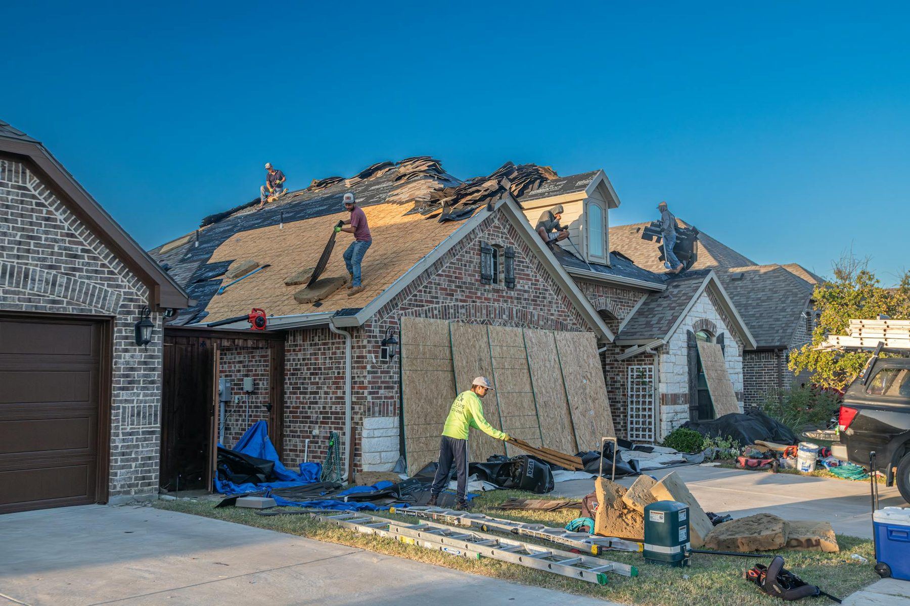Roofers replacing a hail-damaged roof